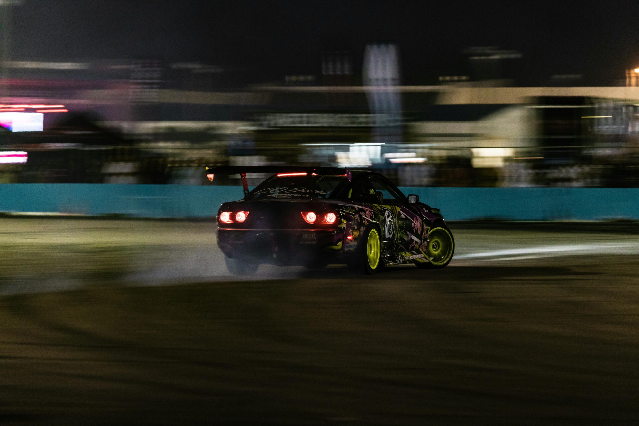 Exciting night drift racing scene captured in West Palm Beach, featuring a high-speed car with vivid colors and motion blur.