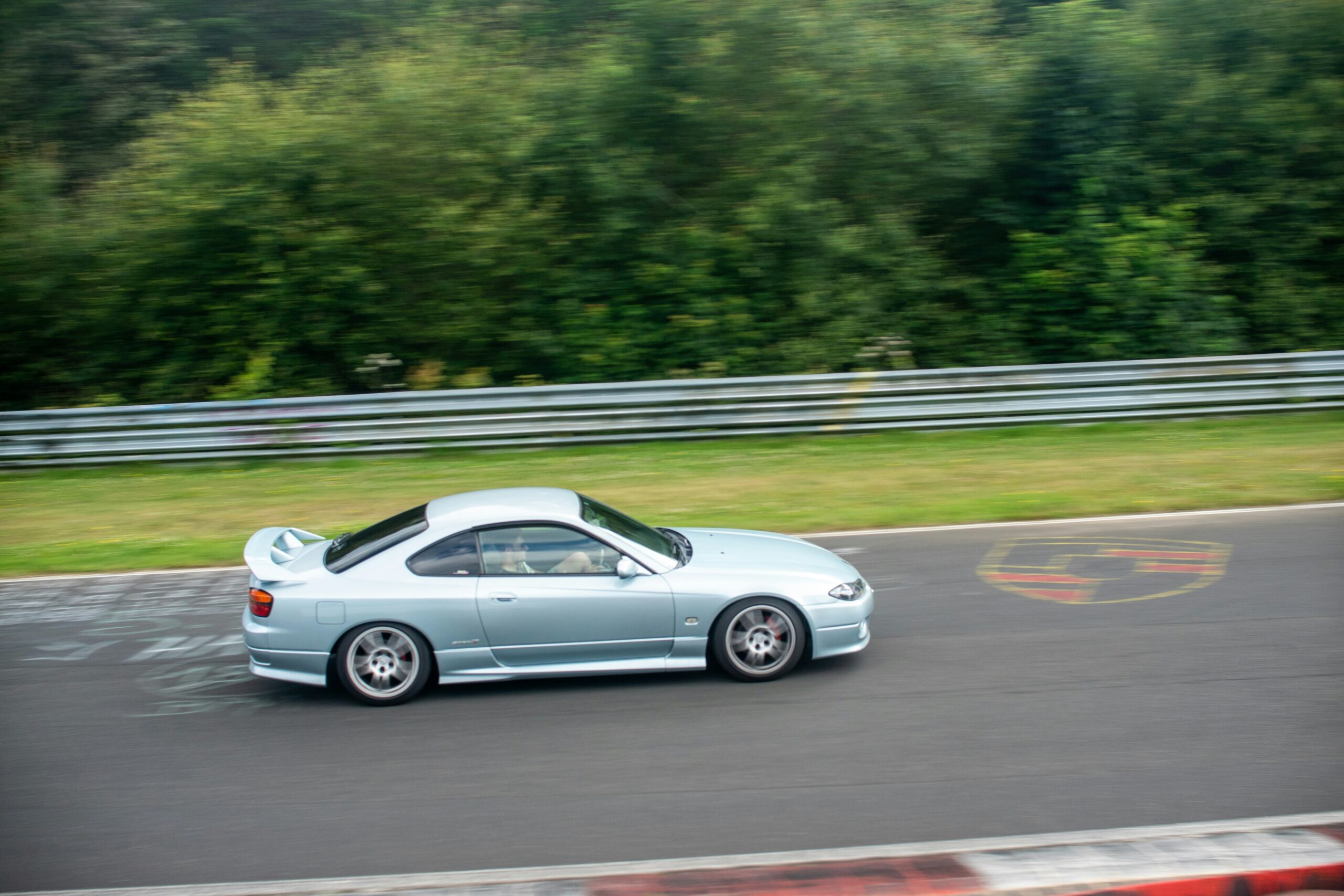 A silver sports car driving down a race track