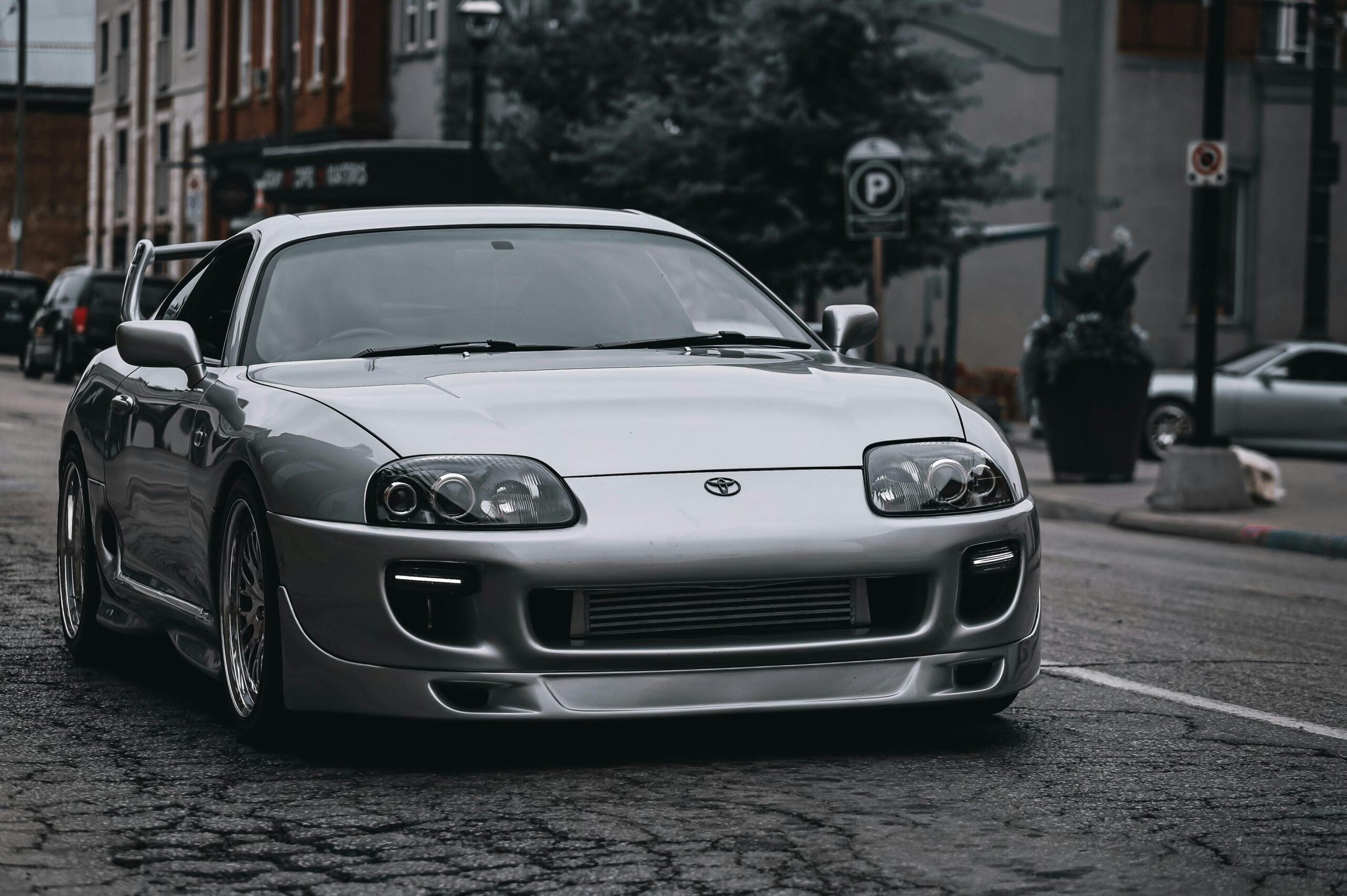 Sleek silver Toyota Supra parked on a gritty urban street, showcasing modern automotive design.