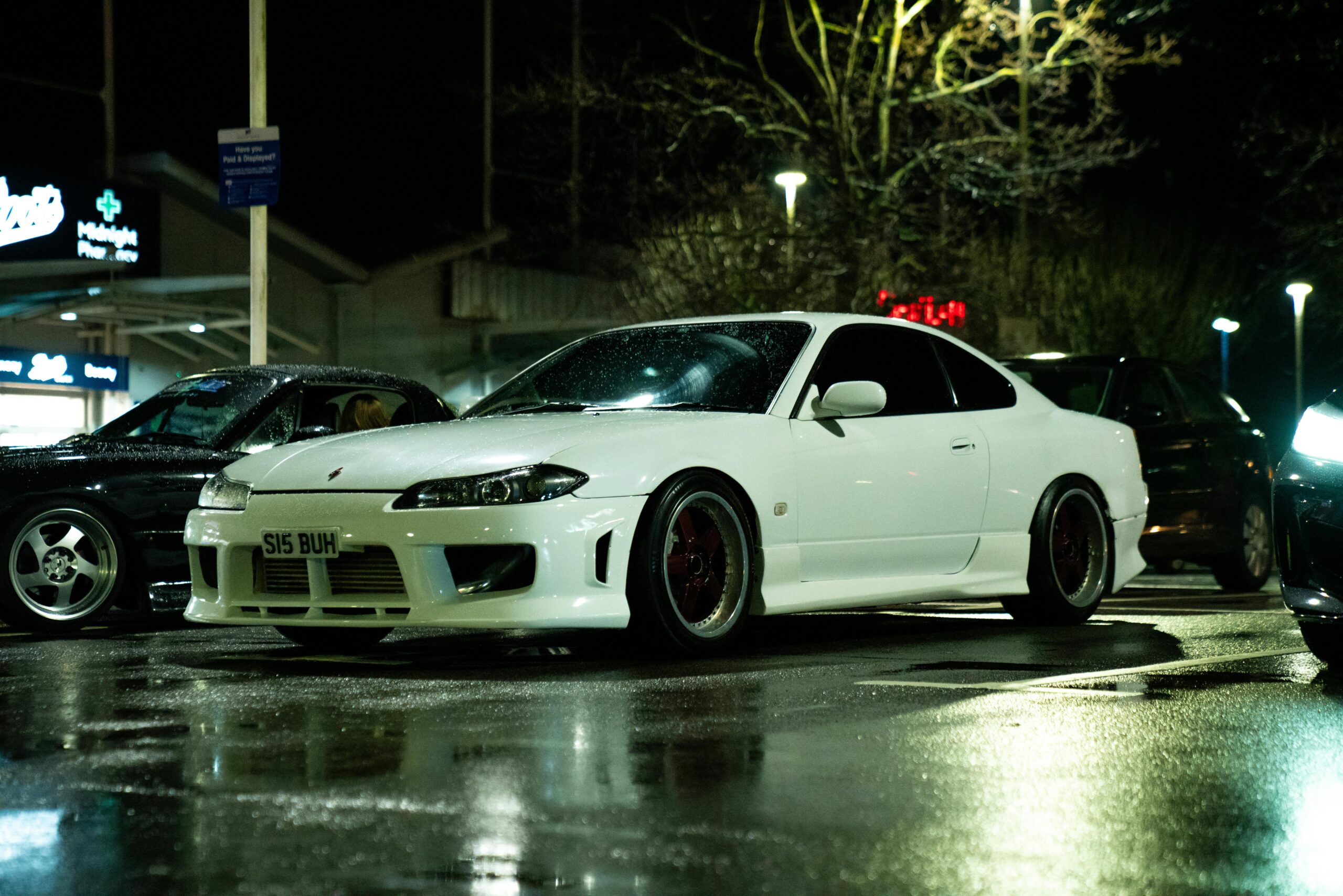 White sports car parked on wet city street at night in Southampton, UK, showcasing urban nightlife.