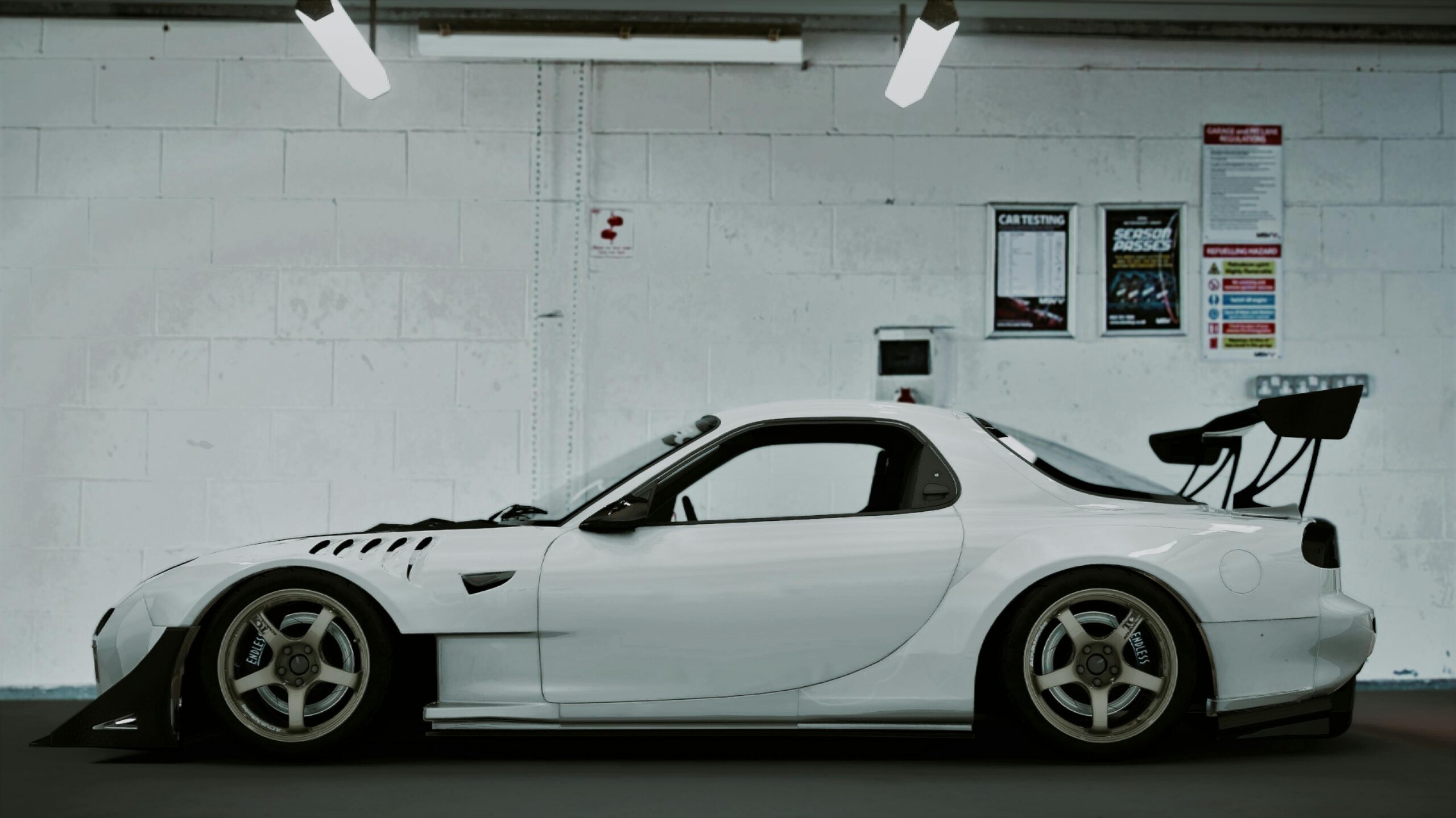 Sleek white Mazda RX-7 parked indoors, captured in a side view.